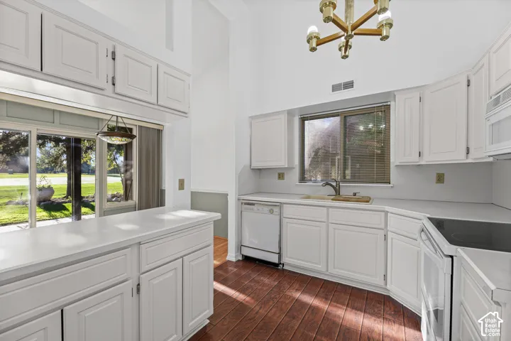 White cabinetry with light countertops, wood-finish flooring, a stainless steel sink, built-in dishwasher, and a glass sliding door