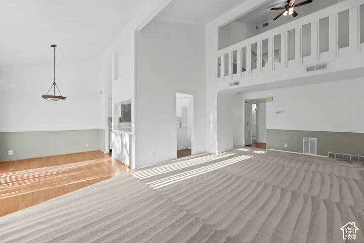 Vaulted ceilings, open concept floor plan, wood-finish flooring, two-tone wall treatment, and an overhead lighting fixture