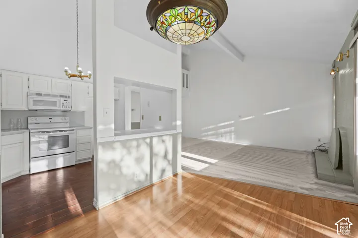 Kitchen with white cabinetry, white appliances, and wood-finish flooring