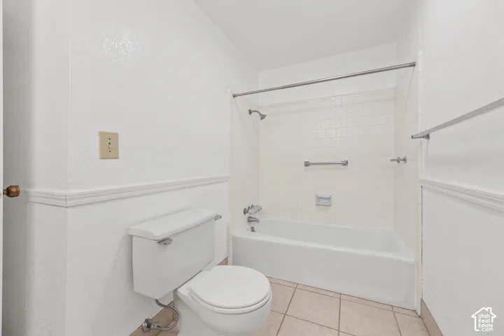 White subway tile tub surround, white bathtub, tile flooring, and wainscoting details