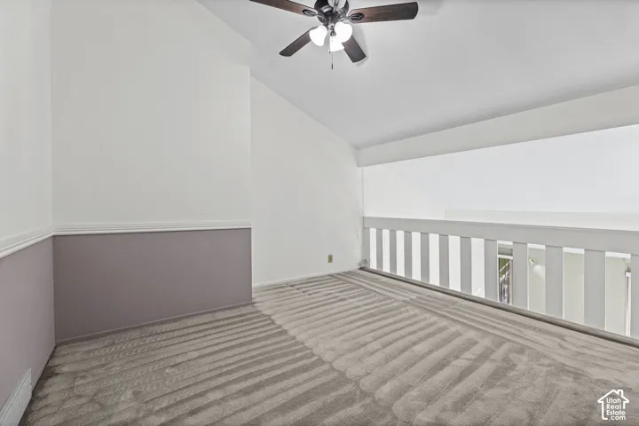 Carpeted loft area with a ceiling fan, white railings, and two-tone wall treatment