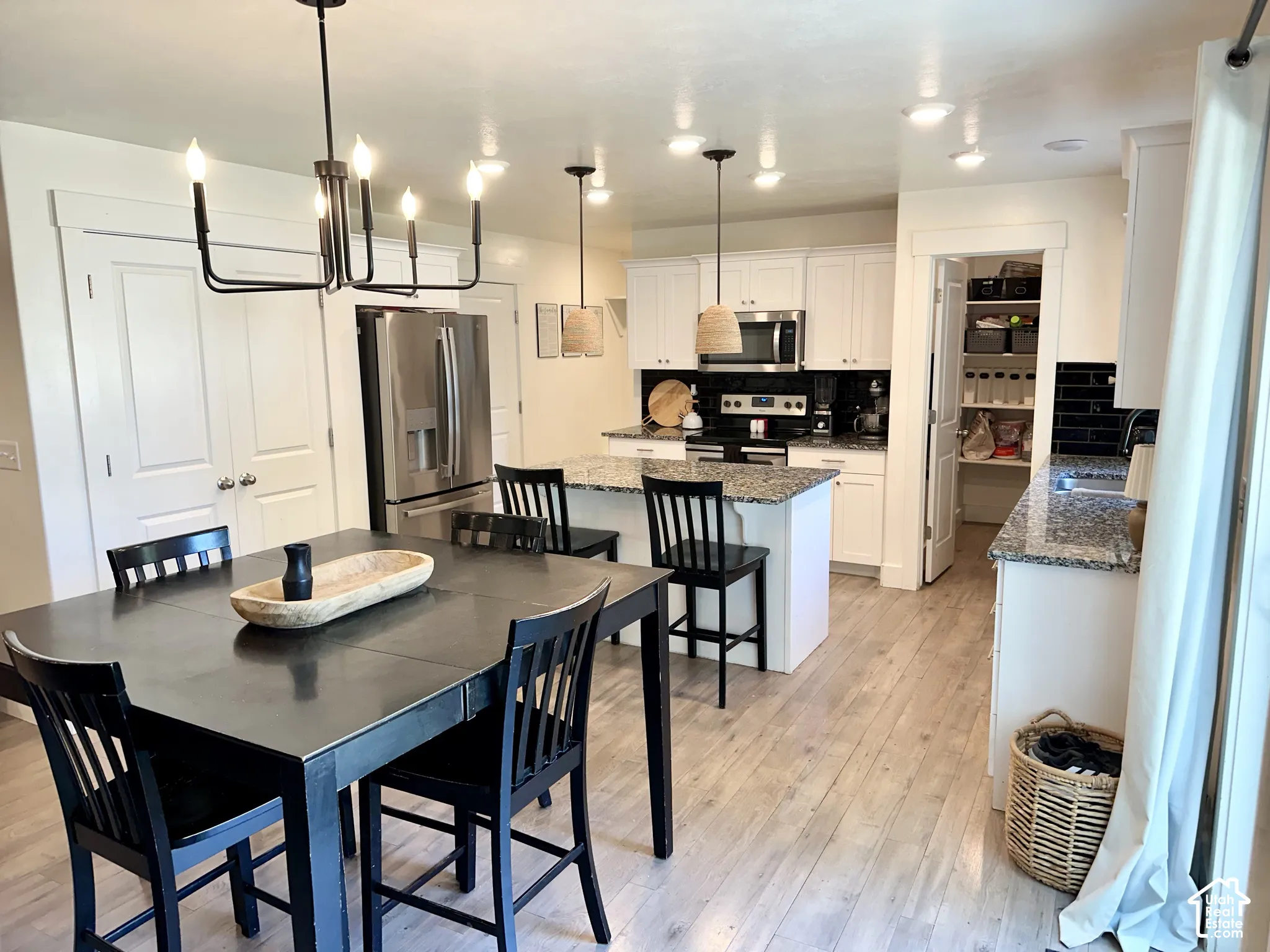 Open-concept design featuring wood-finish flooring, white cabinetry, and granite countertops
