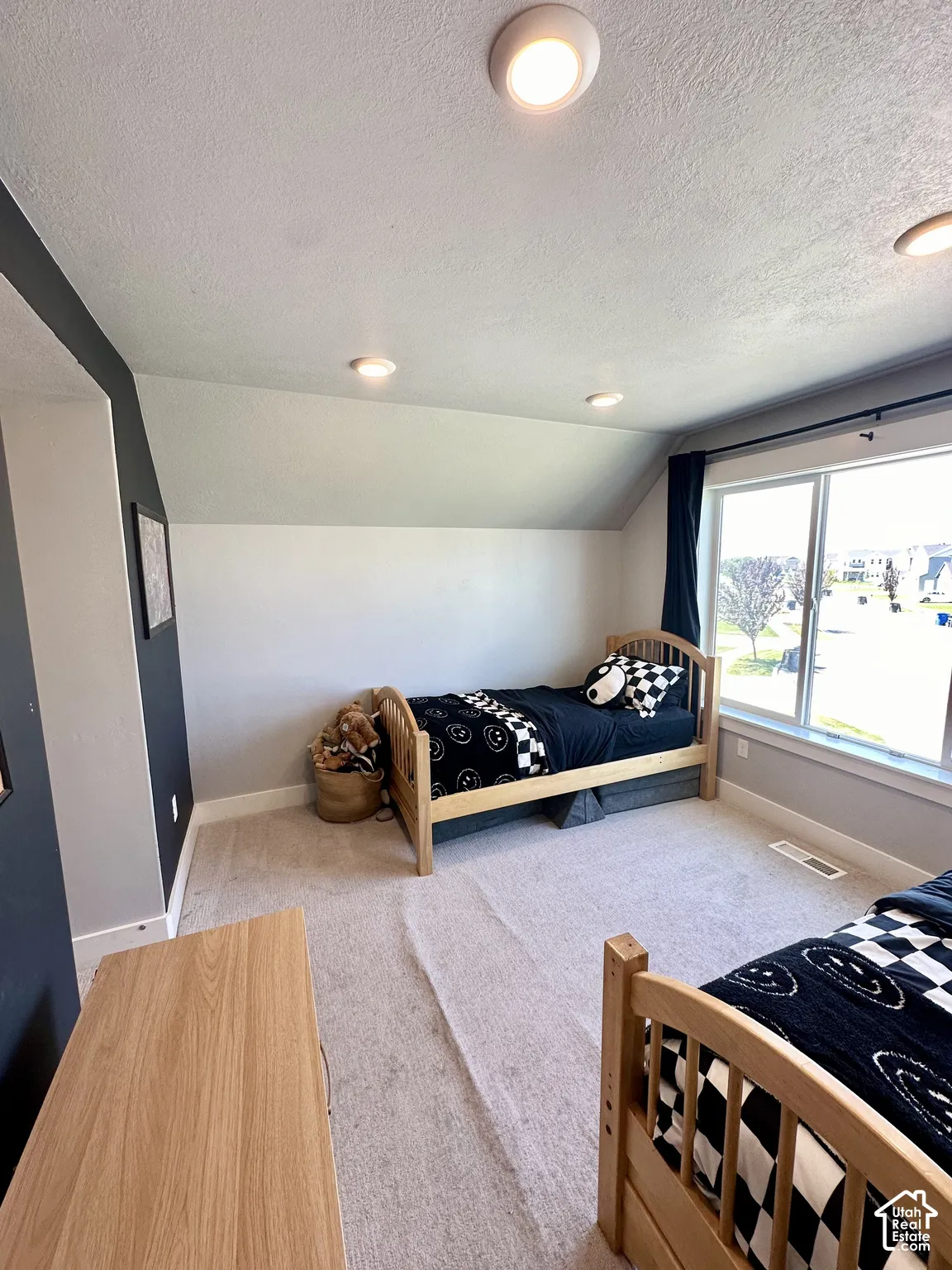 Recessed ceiling lighting, sloped ceiling, large window with natural light, carpeted flooring, and a two-tone wall finish