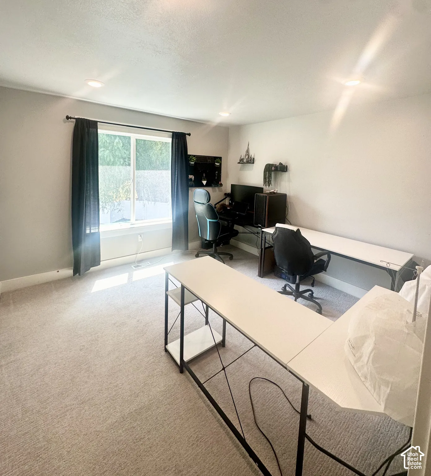 Recessed ceiling lighting illuminates the room with light gray walls and light-toned carpeting