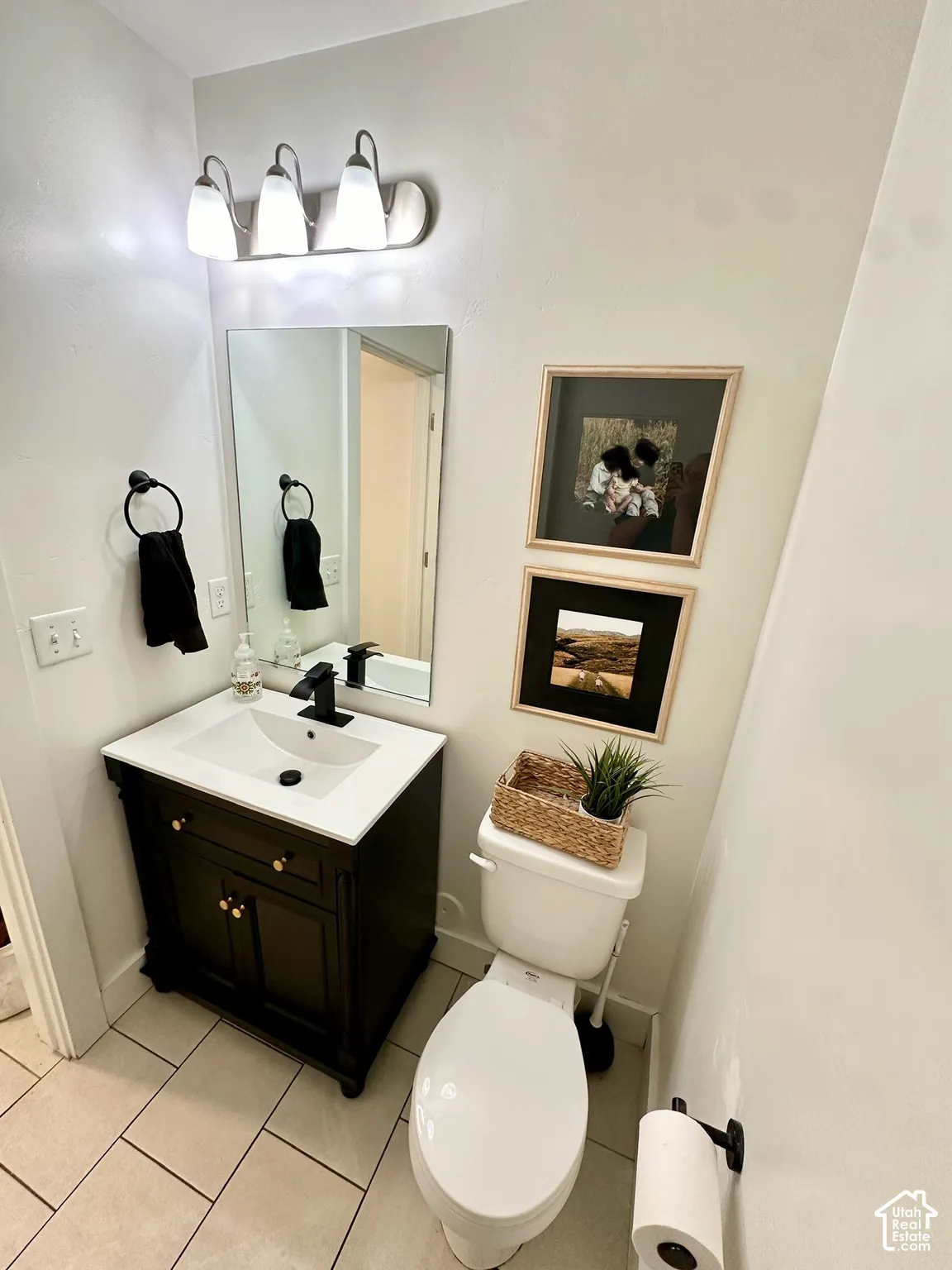 Bathroom featuring a dark wood vanity with white countertop, integrated sink, and modern black faucet