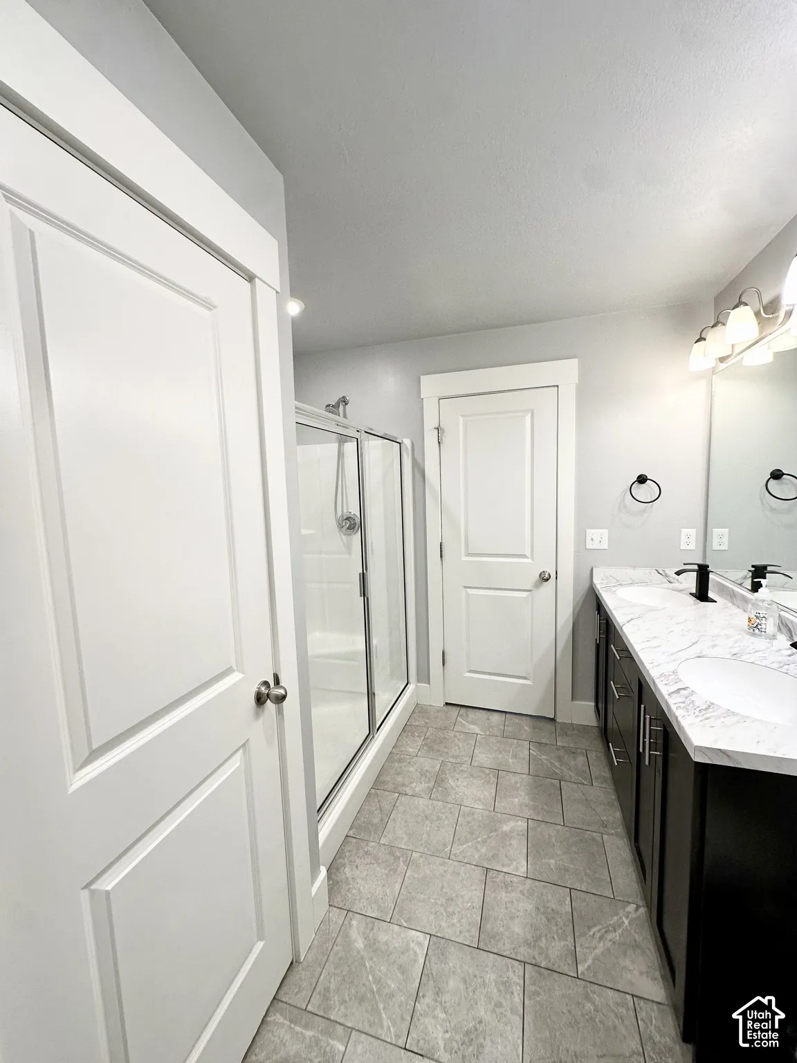 Dual vanity with undermount sinks, stone-look countertop, and dark wood-finish cabinetry