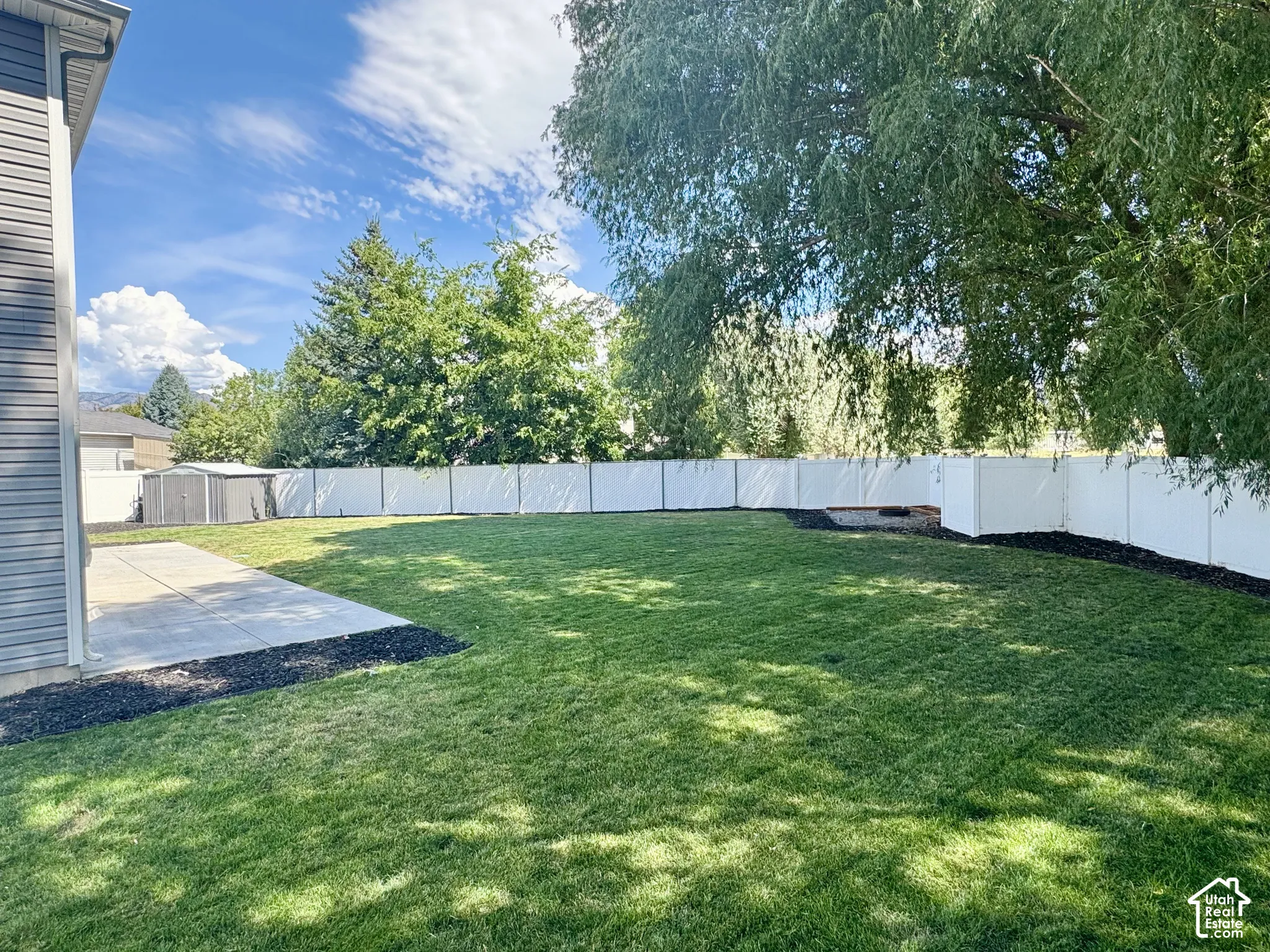 Expansive backyard featuring a manicured lawn, a large concrete patio, and a privacy fence