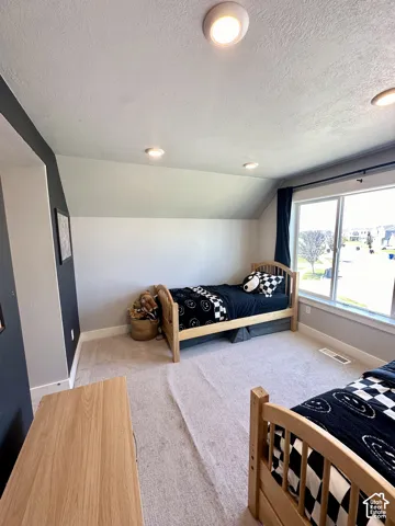 Recessed ceiling lighting, sloped ceiling, large window with natural light, carpeted flooring, and a two-tone wall finish
