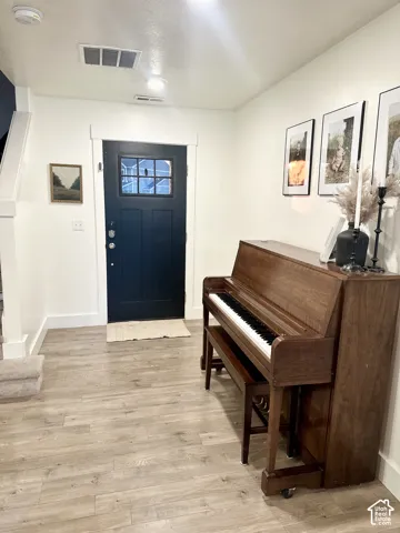 Entryway featuring light wood-finish flooring, a dark paneled door with glass inserts, and recessed lighting