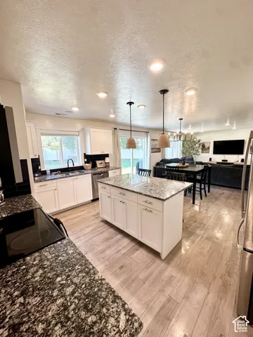 Open-concept kitchen with white cabinetry and dark granite countertops