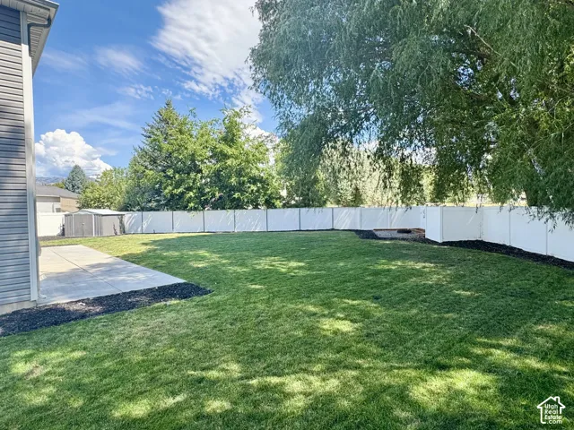 Expansive backyard featuring a manicured lawn, a large concrete patio, and a privacy fence