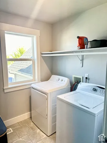 Laundry area featuring a window with white trim, built-in shelving, and tile flooring