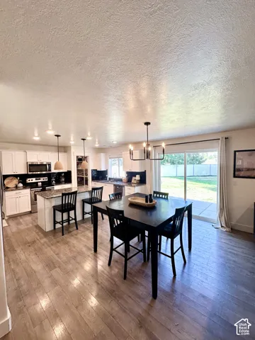 Spacious open-concept area featuring wood-finish flooring, recessed lighting, and a modern chandelier