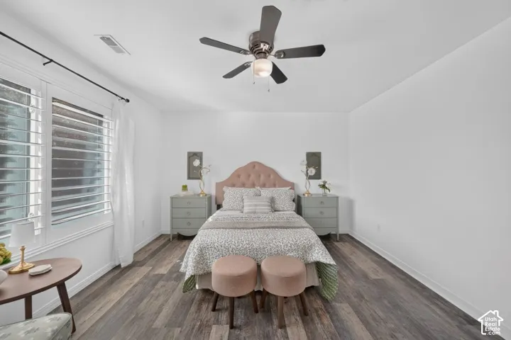 Wood-finish flooring throughout, white walls, and a ceiling fan with integrated lighting