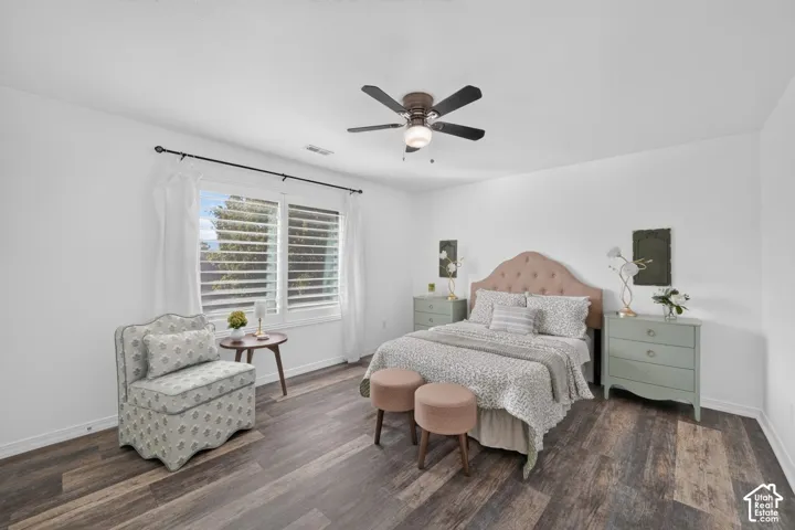 White walls, wood-finish flooring, window with shutters, and a ceiling fan with integrated lighting