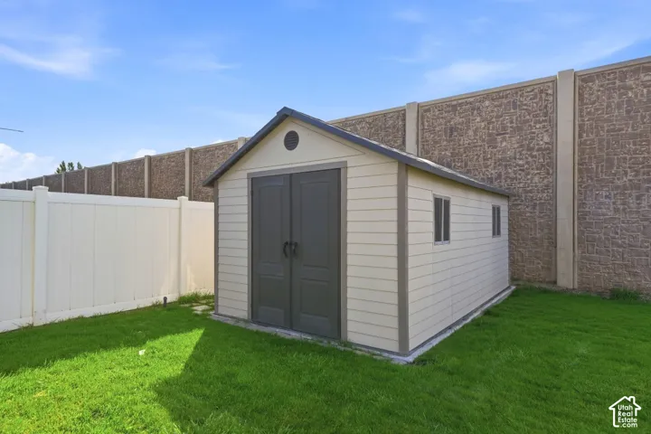 Spacious green lawn featuring a storage shed with dual doors and two windows