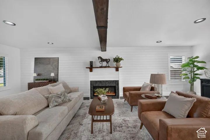 Living area with a wood beam ceiling accent, shiplap wall detailing, recessed lighting, and a fireplace with a dark tile surround and wood mantel