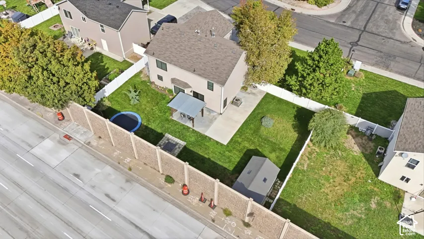 Expansive backyard with a covered patio, concrete hardscaping, a detached storage shed, and a privacy fence