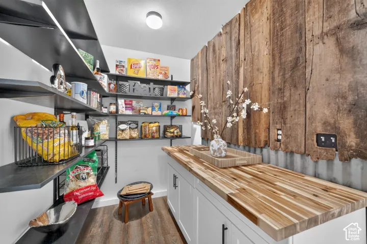 Wood-finish countertop with white cabinetry, corrugated metal wainscoting, and wood plank wall accent