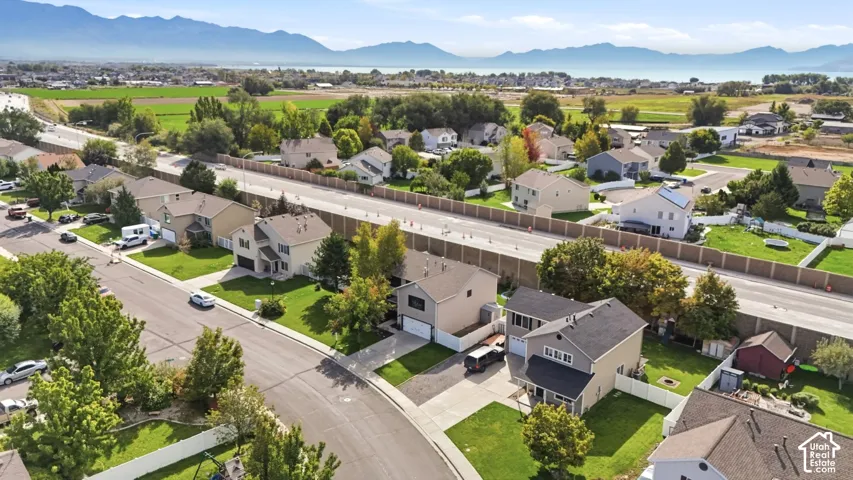 Residential neighborhood with varied architectural styles, green landscaping, and distant mountain and water scenery
