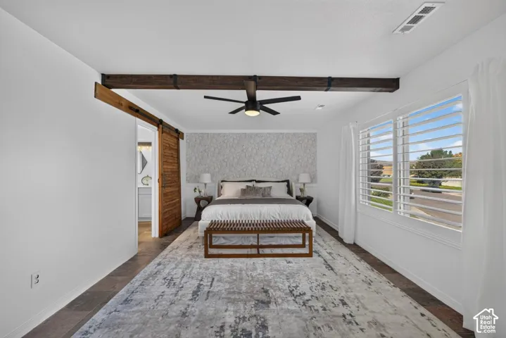 Exposed wood-finish ceiling beams, wood-finish barn door, white plantation shutters, textured accent wall, and ceiling fan