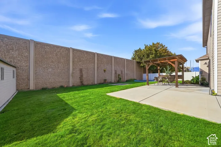 Expansive backyard featuring a lush lawn, concrete patio, and a wooden pergola structure