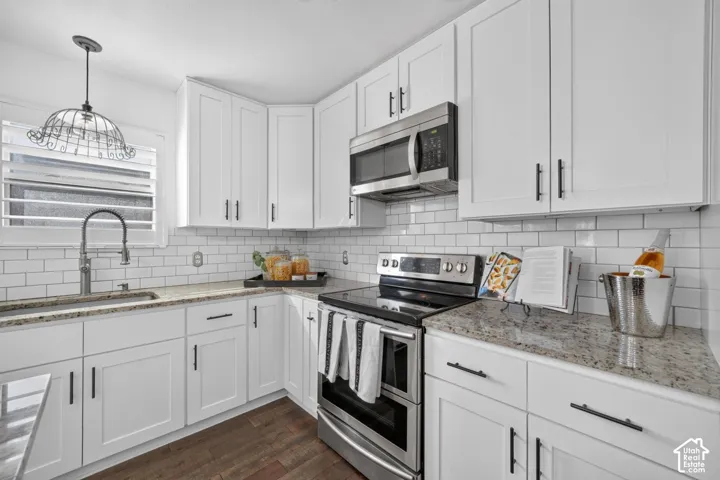 White shaker cabinetry, granite countertops, subway tile backsplash, stainless steel appliances, and wood-finish flooring