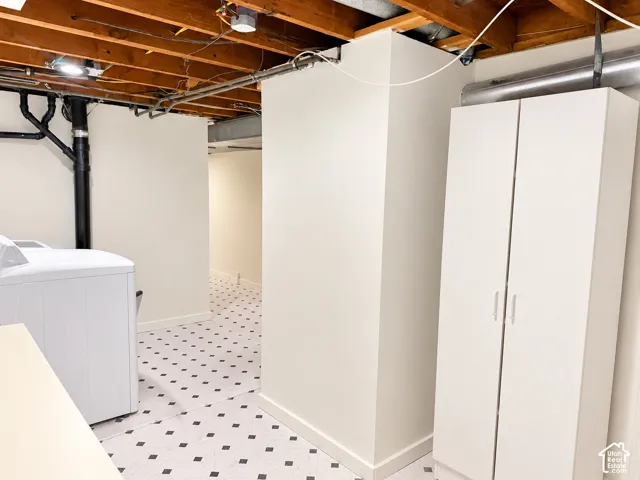 Utility area featuring an exposed beam ceiling, built-in shelving, washer/dryer