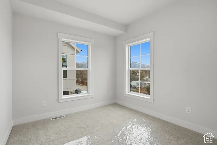 Neutral wall paint, two double-hung windows, white trim, and light-colored carpeting