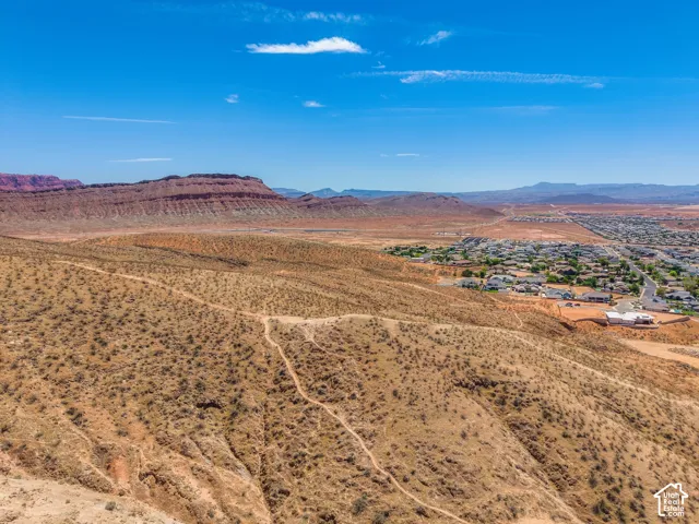 Expansive desert landscape with distant red rock formations and a community of properties