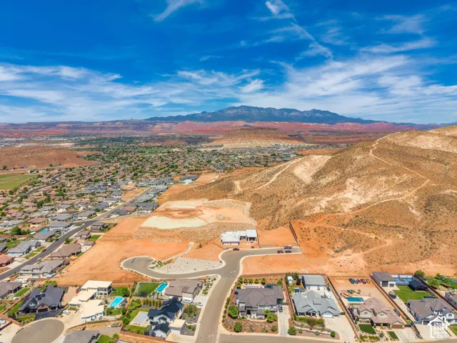 Expansive undeveloped land parcels with surrounding residential properties, paved roads, and distant mountain ranges
