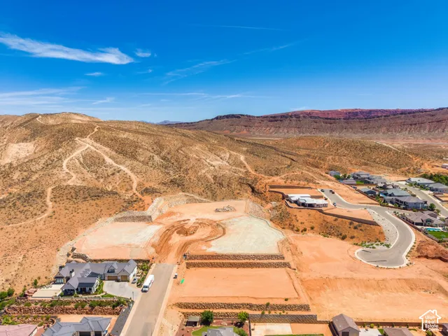 Expansive residential development featuring graded lots and paved streets, surrounded by natural desert landscape and distant mountains