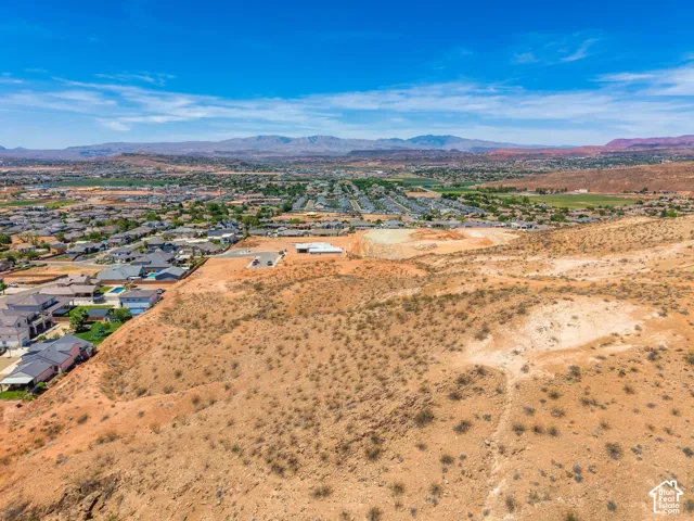 Expansive undeveloped land with a distant residential neighborhood and mountainous terrain