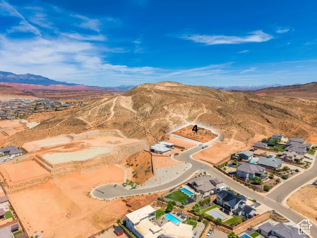 Expansive land parcel with surrounding desert landscape, distant mountain range, and nearby residential development