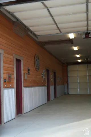 Wood-panel walls with corrugated wainscoting, a concrete floor, and multiple overhead light fixtures