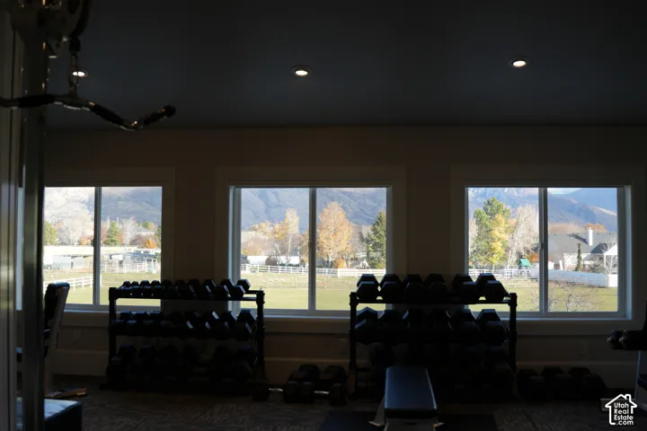 Three large windows with white trim, recessed ceiling lighting, and wall-to-wall carpeting