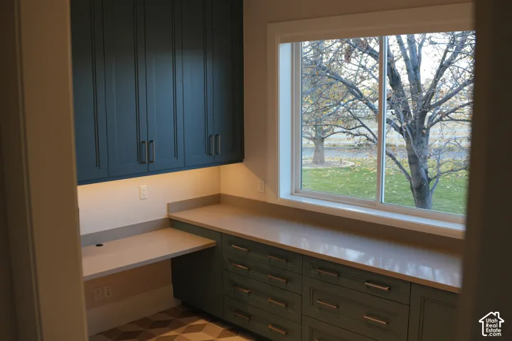 Built-in cabinetry with under-cabinet lighting, extensive countertop space, multiple storage drawers, and a large window