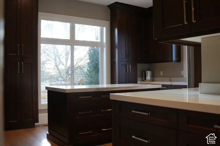 Dark wood-finish cabinetry, white countertops, and a central island with storage drawers