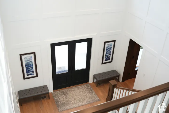 Two-story entryway featuring wood-finish flooring, wainscoting, and a prominent double door with opaque glass