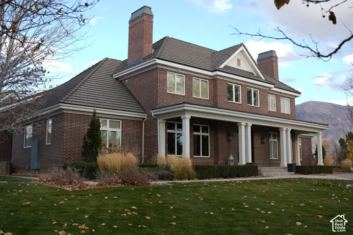 Brick exterior with white trim, covered front porch with columns, multiple gabled rooflines, and prominent chimneys