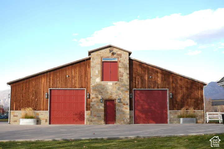 Two red garage doors, a red access door, and a red window, all contrasting with the wood-paneled exterior and stone facade