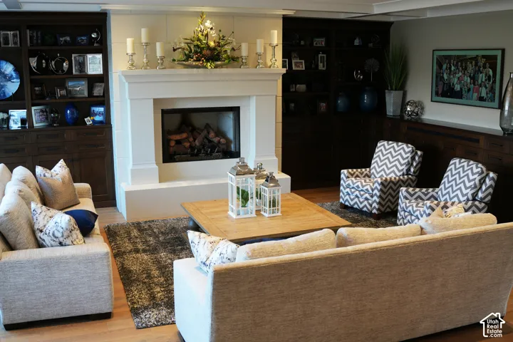 Central fireplace with a stone surround, built-in shelving, wood-finish flooring, and recessed lighting