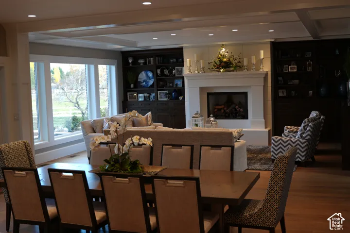 Hardwood flooring, recessed lighting, coffered ceiling, large windows, and a stone fireplace