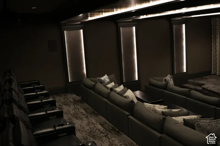 Theater room featuring tiered seating, recessed wall lighting, and dark wall finishes