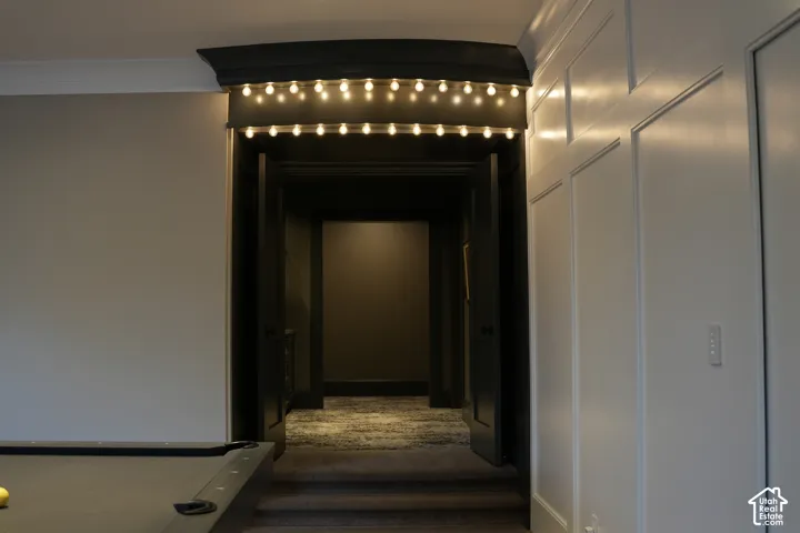 Decorative archway with string lighting, paneled wall detailing, and a dark-toned interior corridor