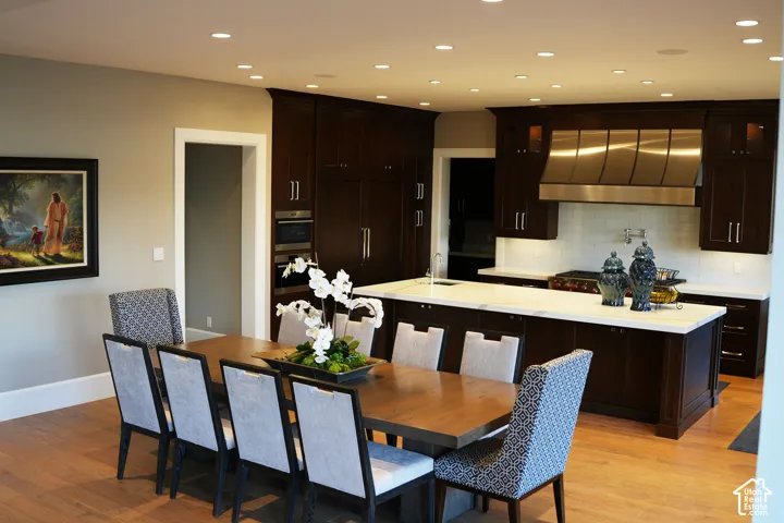 Hardwood-finish flooring, recessed lighting, dark wood-finish cabinetry, stainless steel range hood, and light-toned countertops