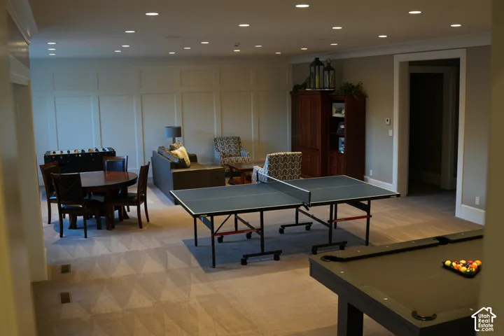 Spacious entertainment area featuring recessed lighting, paneled accent wall, neutral carpeting, and a built-in wood-finish cabinet