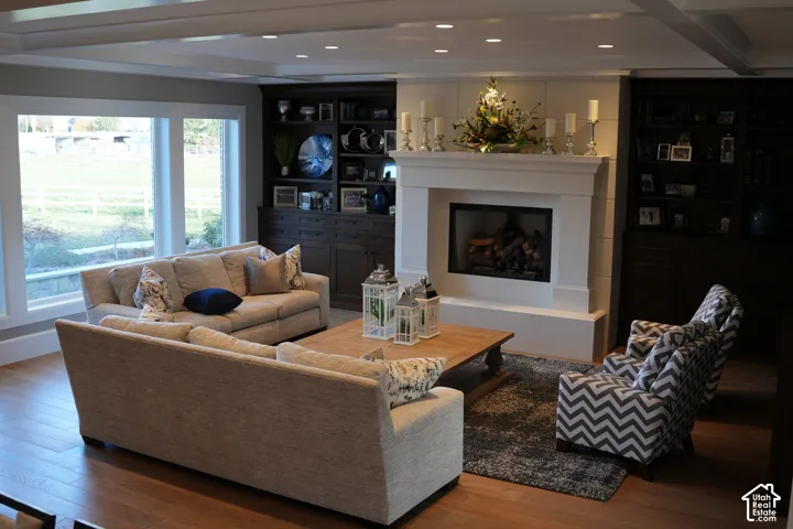 Hardwood flooring, recessed ceiling lighting, large windows, built-in shelving, and a fireplace with a mantel
