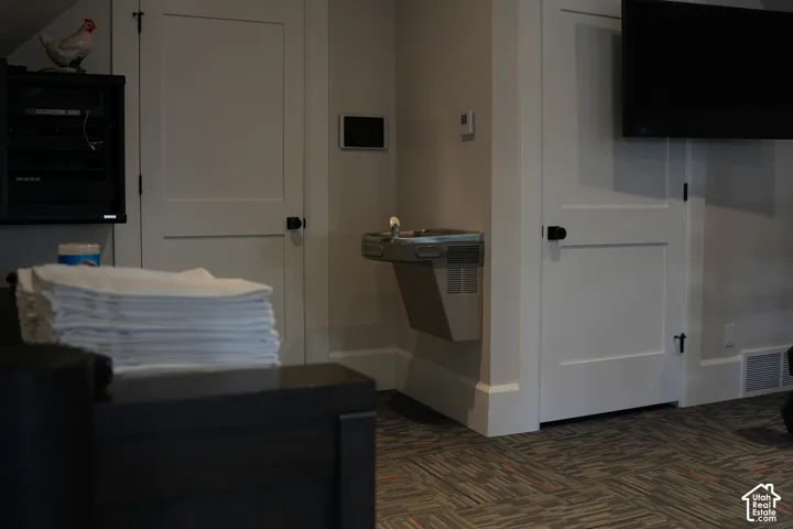 Recessed water fountain, paneled interior doors with matte black hardware, wall-mounted television, and patterned carpet flooring