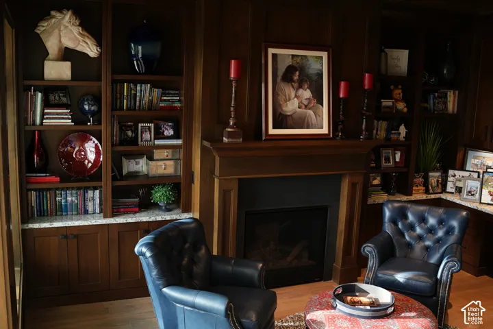 Built-in wood cabinetry with integrated shelving, fireplace with wood mantel, and wood-finish flooring
